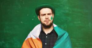 Man draped in Irish flag with shamrock painted on his face