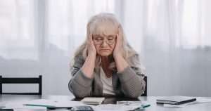 Older woman looking at bills after government demands return of carer's allowance