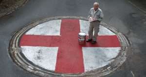 man painting st georges cross on a mini roundabout