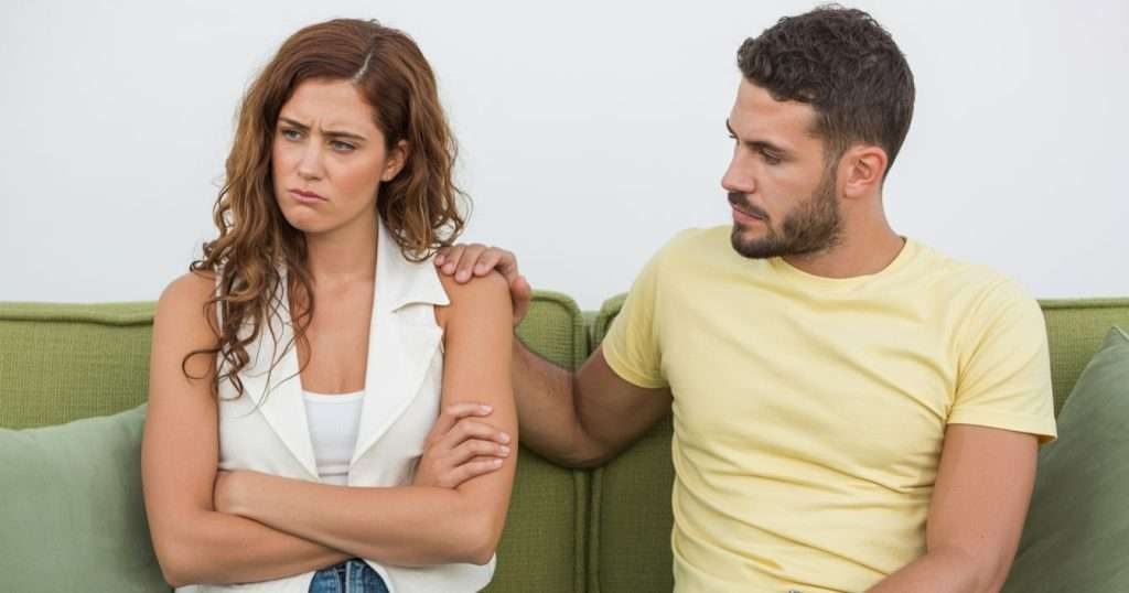 man apologising to partner on sofa