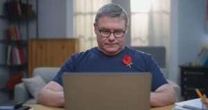 Mark Francois at his laptop with a poppy
