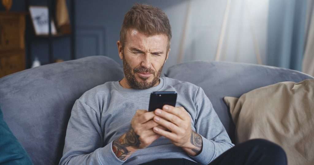 David beckham looking at his phone confused