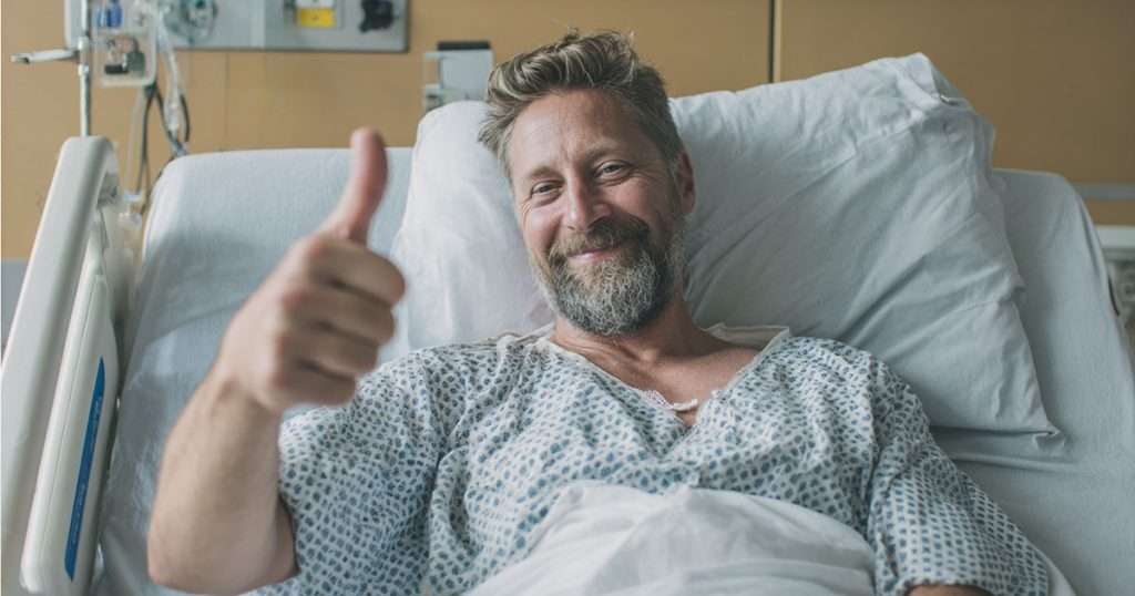 man in hospital bed with thumbs up